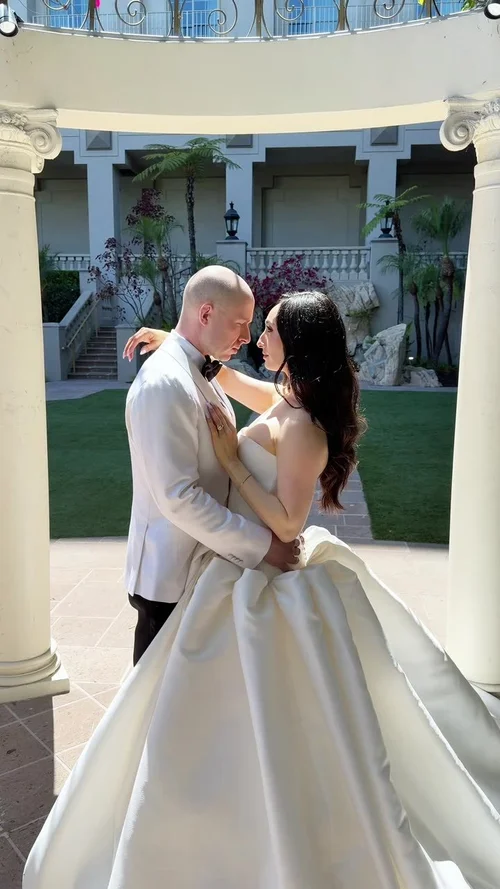 A couple embracing on the lawn of a white villa, filmed vertically on a phone