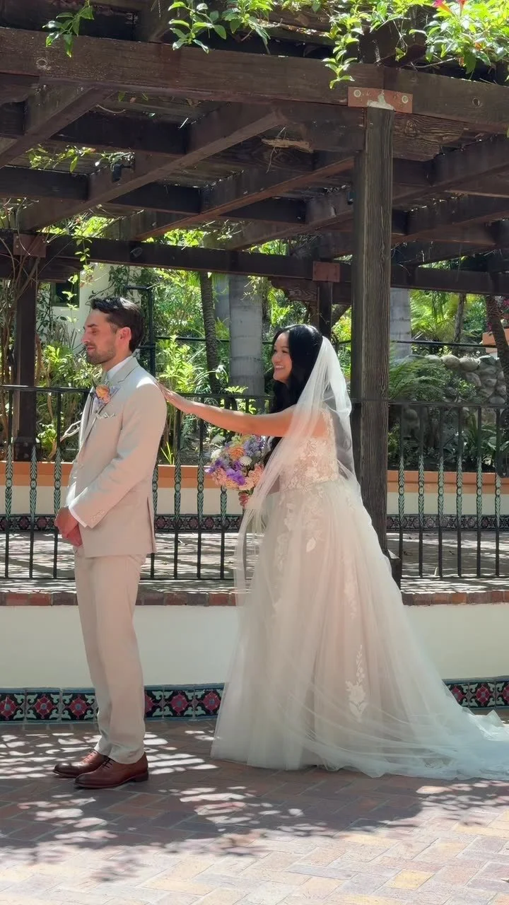 A couple at their first look beneath a garden pergola, filmed vertically on a phone