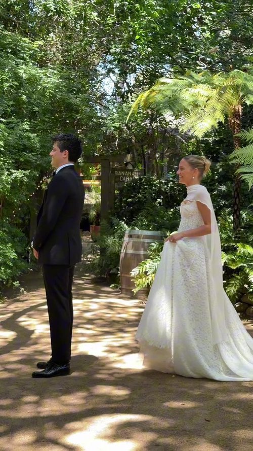 A couple facing each other on a shaded garden path, filmed vertically on a phone