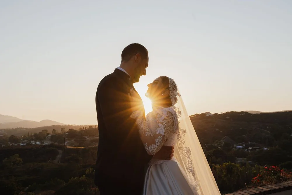 Couple silhouetted against the sun over the hills at golden hour
