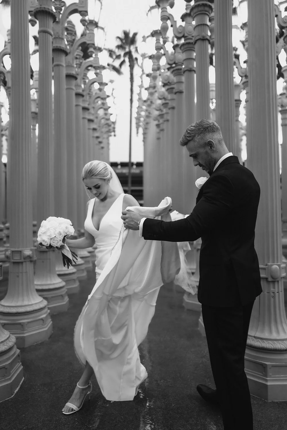 Black and white photograph of a couple among the cast-iron lamps of Urban Light at LACMA