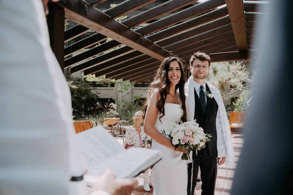 Bride and groom seated together during the ketubah signing, the document in the foreground