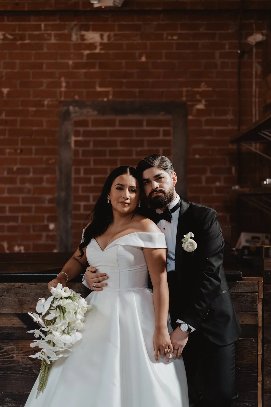 Couple against the red brick wall and dark wood trim at Seventh Place, Los Angeles