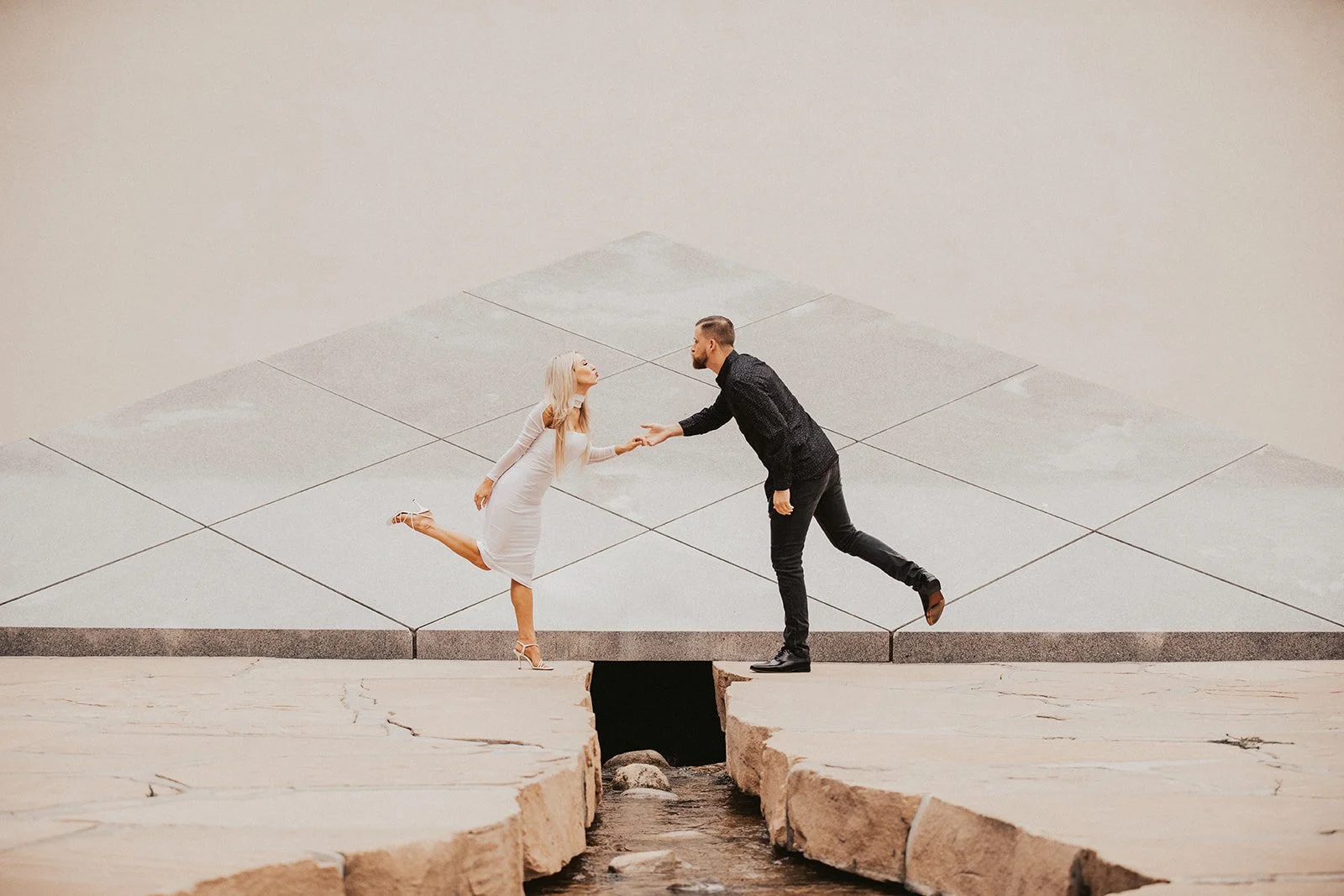 Couple mid-step across the stone plaza of California Scenario, the Noguchi Garden in Costa Mesa