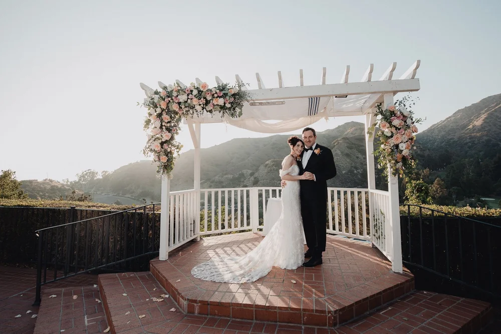 Ceremony under the white pergola at Castaway Burbank with the Verdugo hills behind
