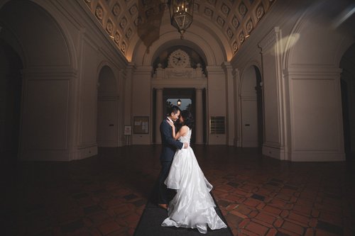 Bride standing alone in a lit archway at Pasadena City Hall after dark