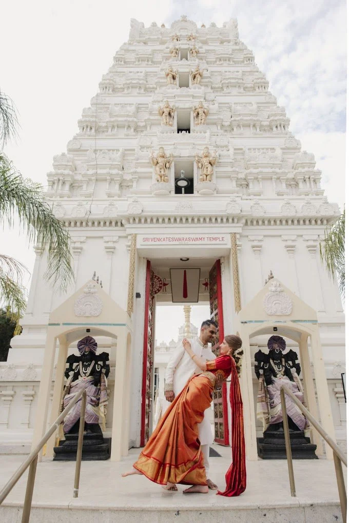 Couple at the gateway of a Hindu temple as the priest leads them in