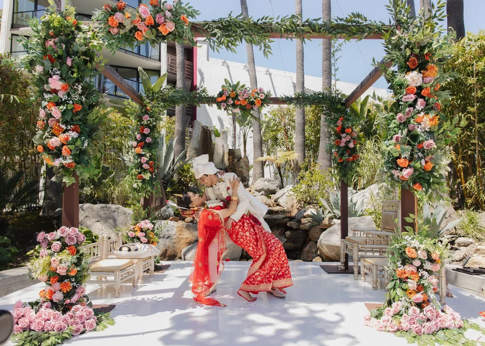 Couple under a floral mandap in the palm courtyard at Hotel Maya in Long Beach