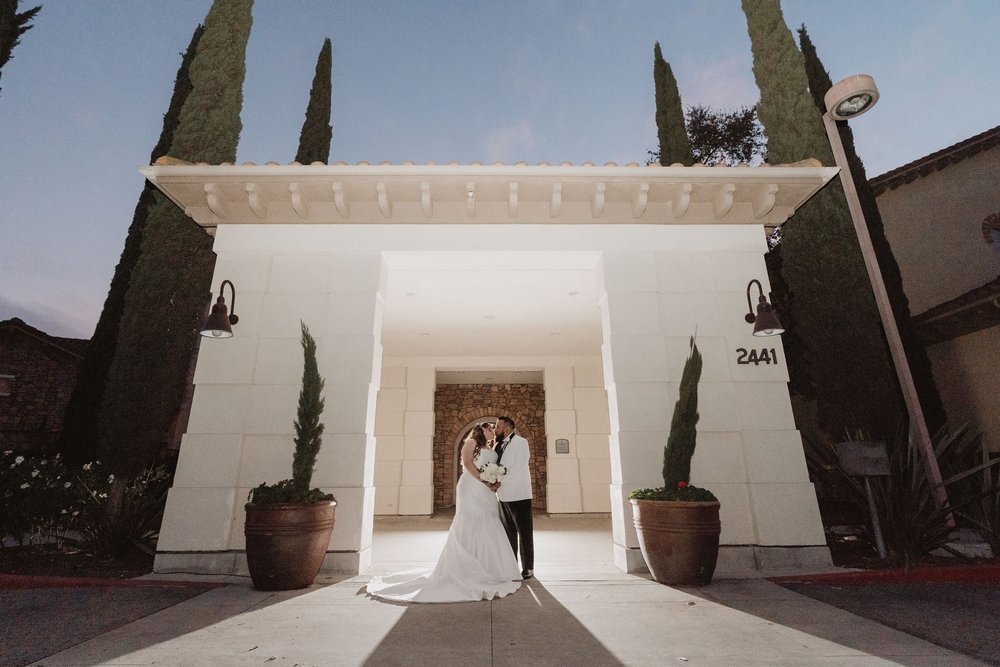 The lit stone entry flanked by cypress trees and terracotta pots at Vellano Estate in Chino Hills