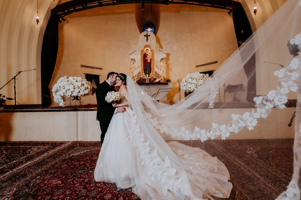 Bride and groom at the altar of an Armenian church, her long veil sweeping across the carpet