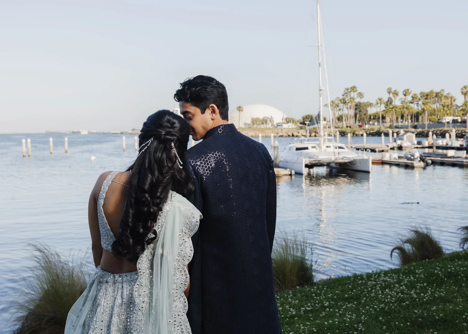 Couple on the waterfront lawn looking across the marina at Hotel Maya