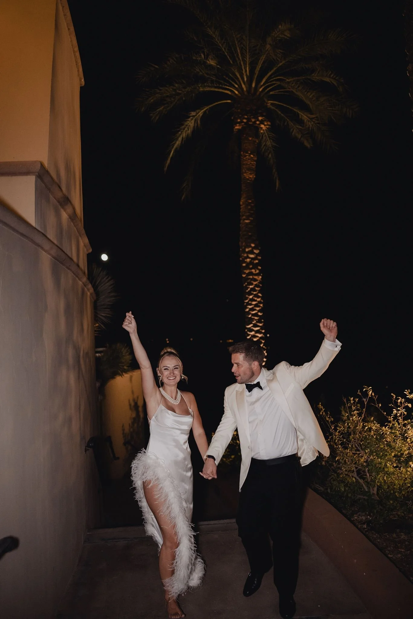 Couple celebrating on a walkway under palms at night at Westin Lake Las Vegas