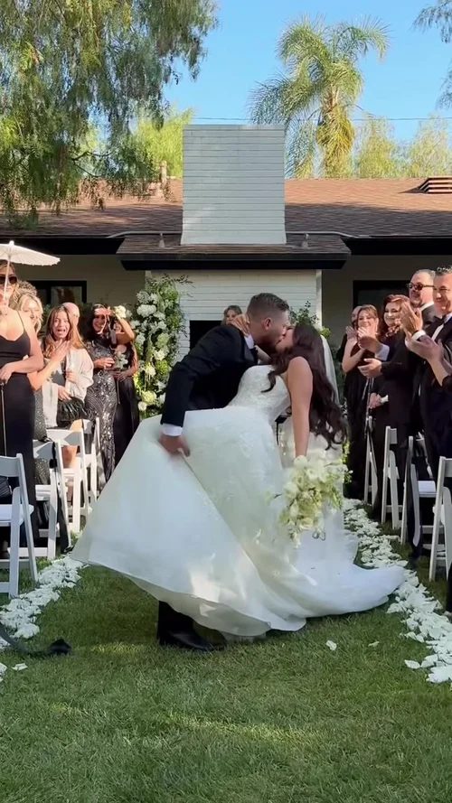 The newlyweds kissing as they come back down the aisle while their guests cheer
