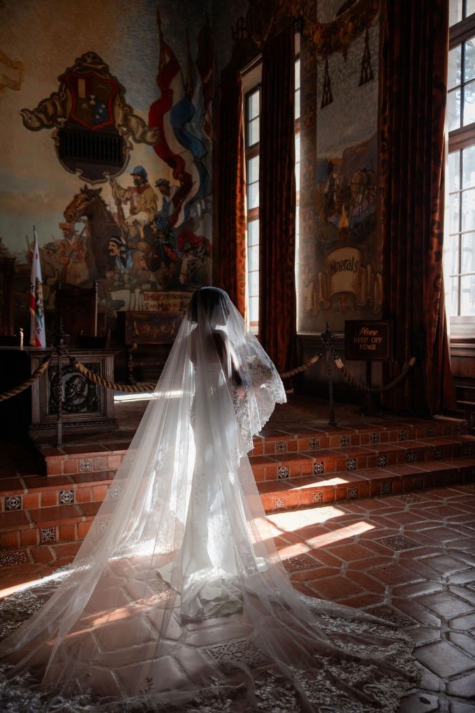 Bride in a cathedral veil in a sunlit historic tiled hall