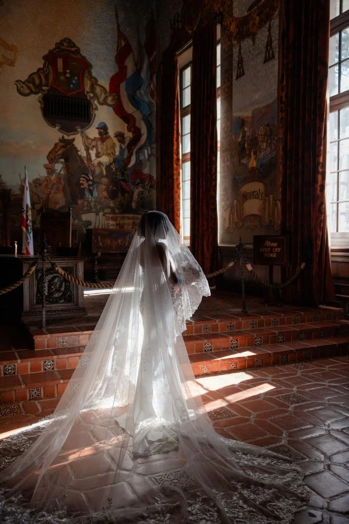 Bride in a cathedral veil in a sunlit historic tiled hall