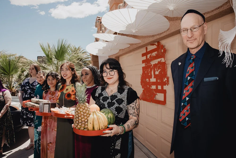 Family carrying the red mam qua gift trays of fruit into the bride’s home for the Vietnamese engagement ceremony