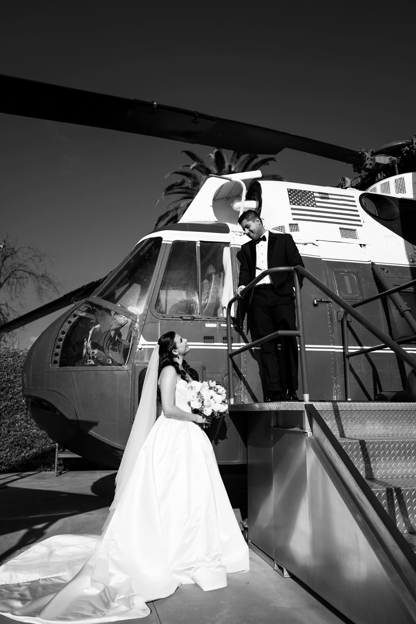 Bride at the foot of the helicopter stairs with the groom above, black and white, Nixon Library