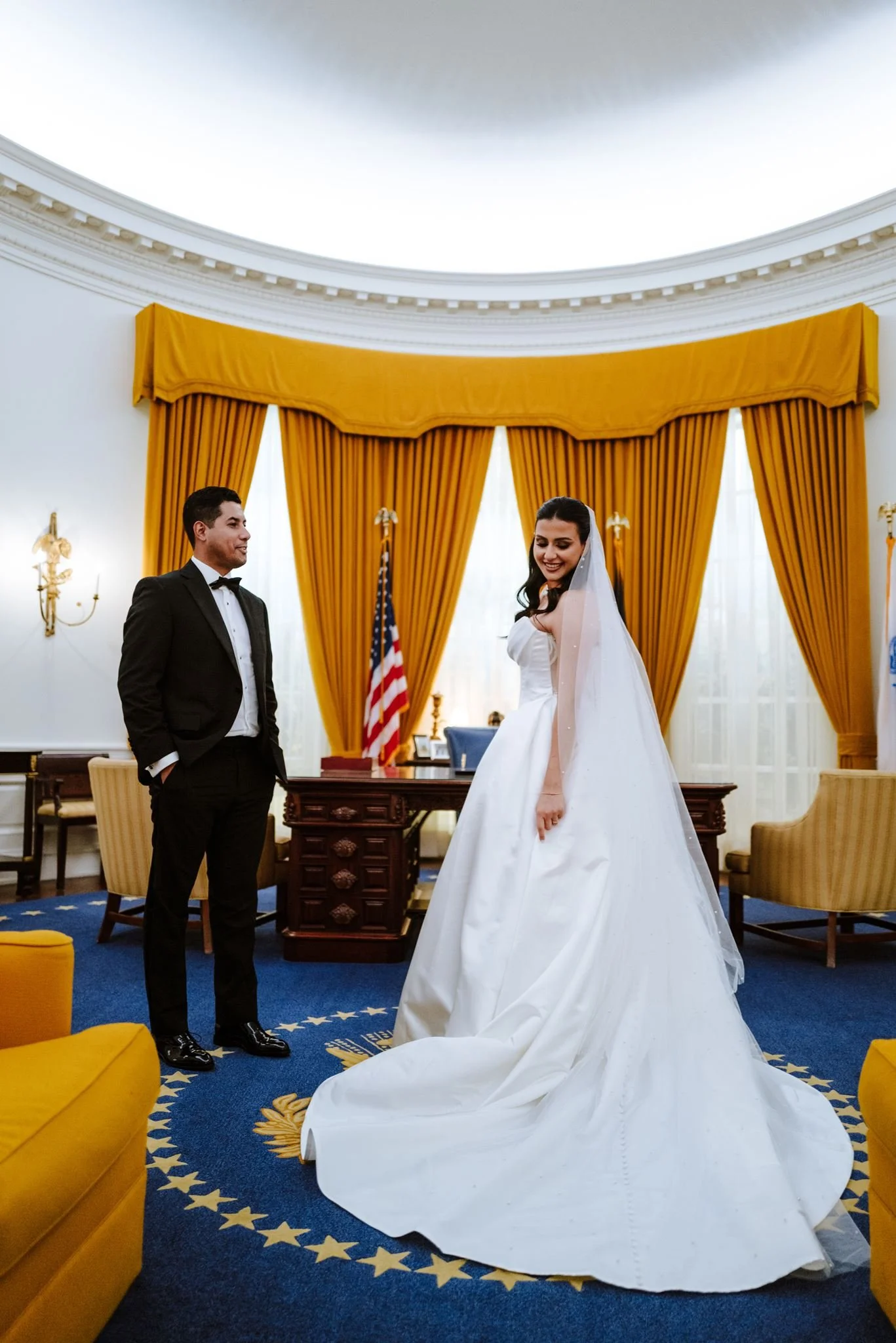 Couple in the Oval Office replica with gold drapes and a blue star rug at the Nixon Library