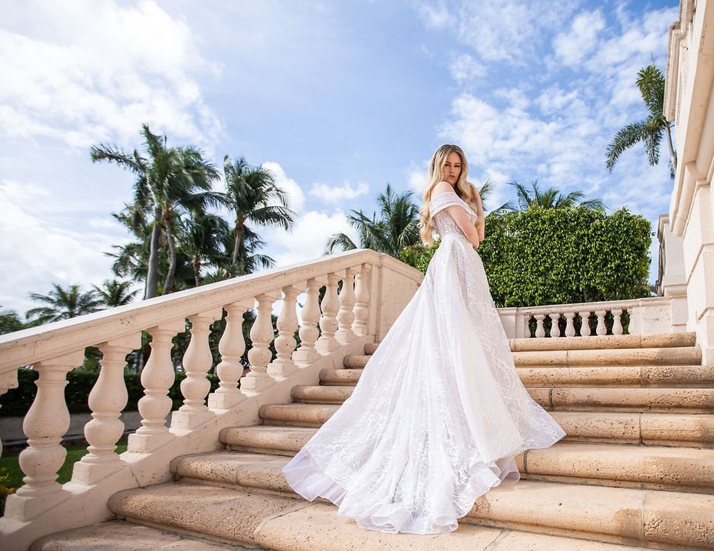 Bride on a sweeping stone staircase framed by palms