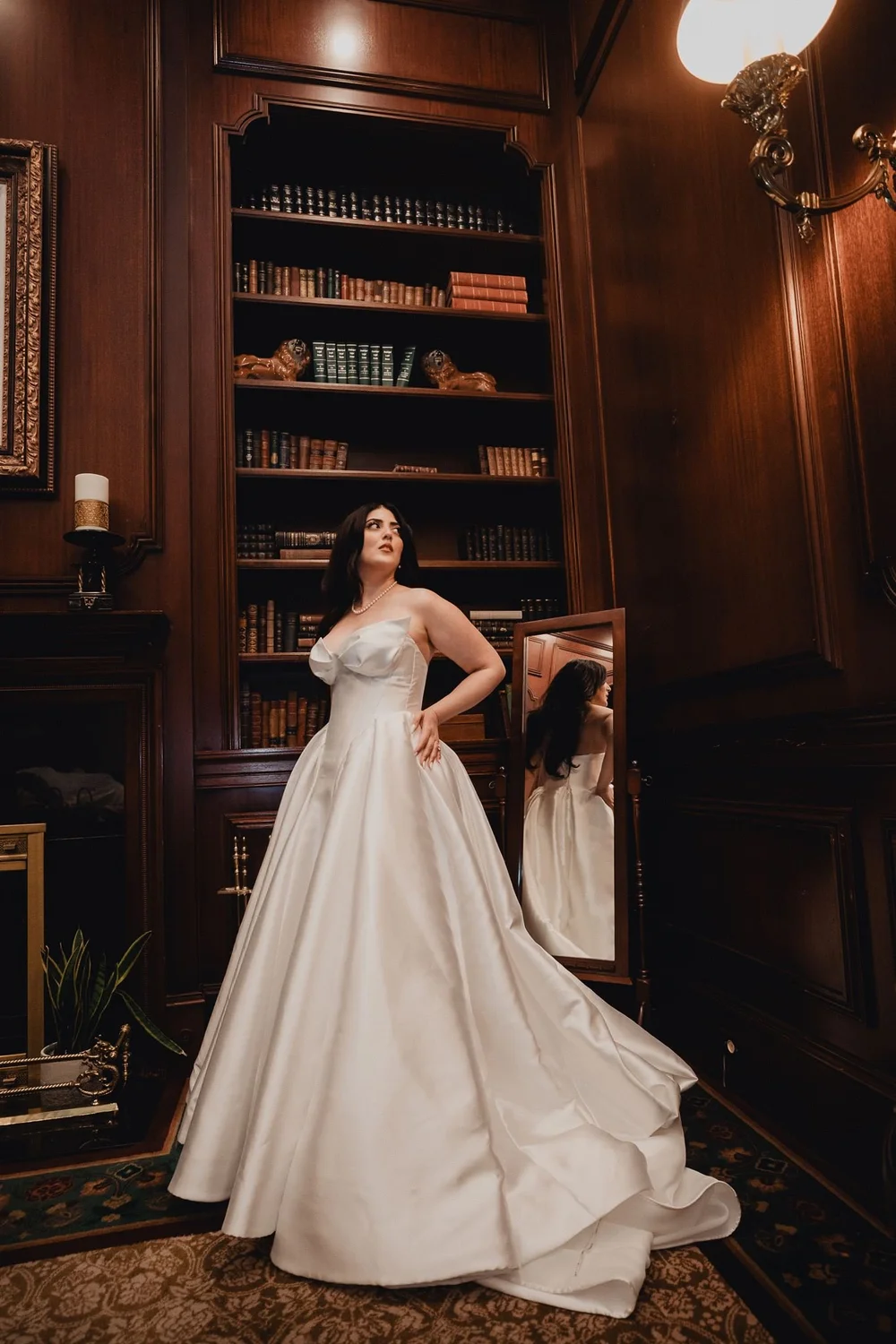 Bride in a structured ivory silk princess A-line gown standing in a wood-panelled library