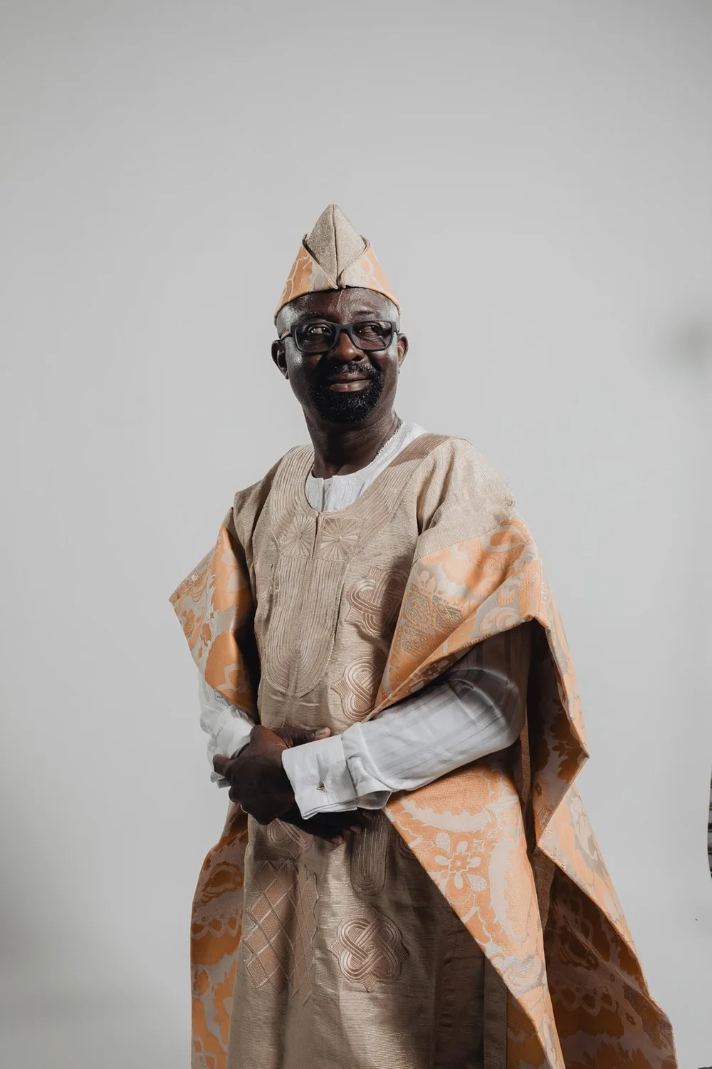 Portrait of the groom smiling in a peach damask agbada and matching fila