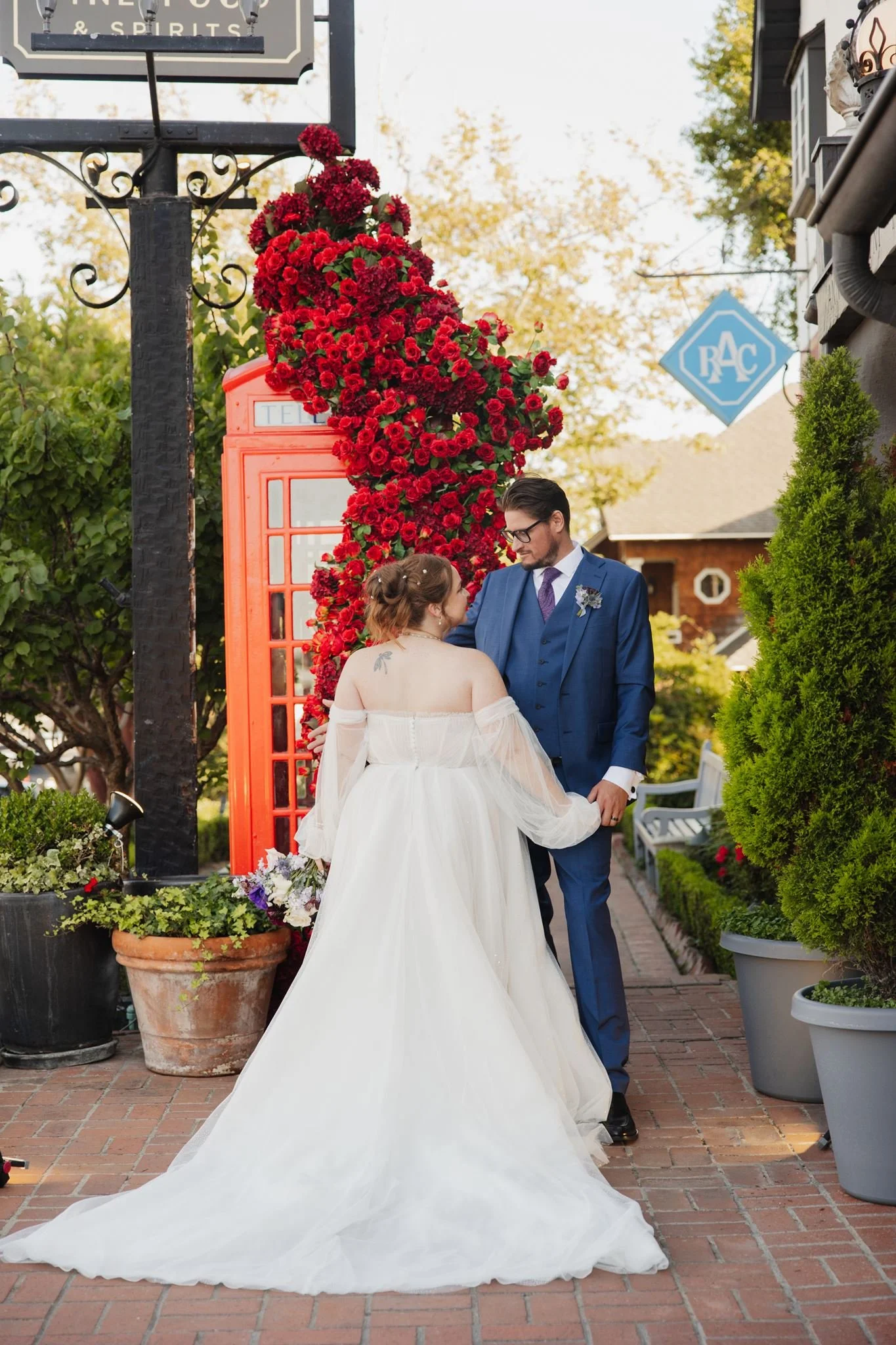Couple walking hand in hand past the red phone box and lantern post at Five Crowns
