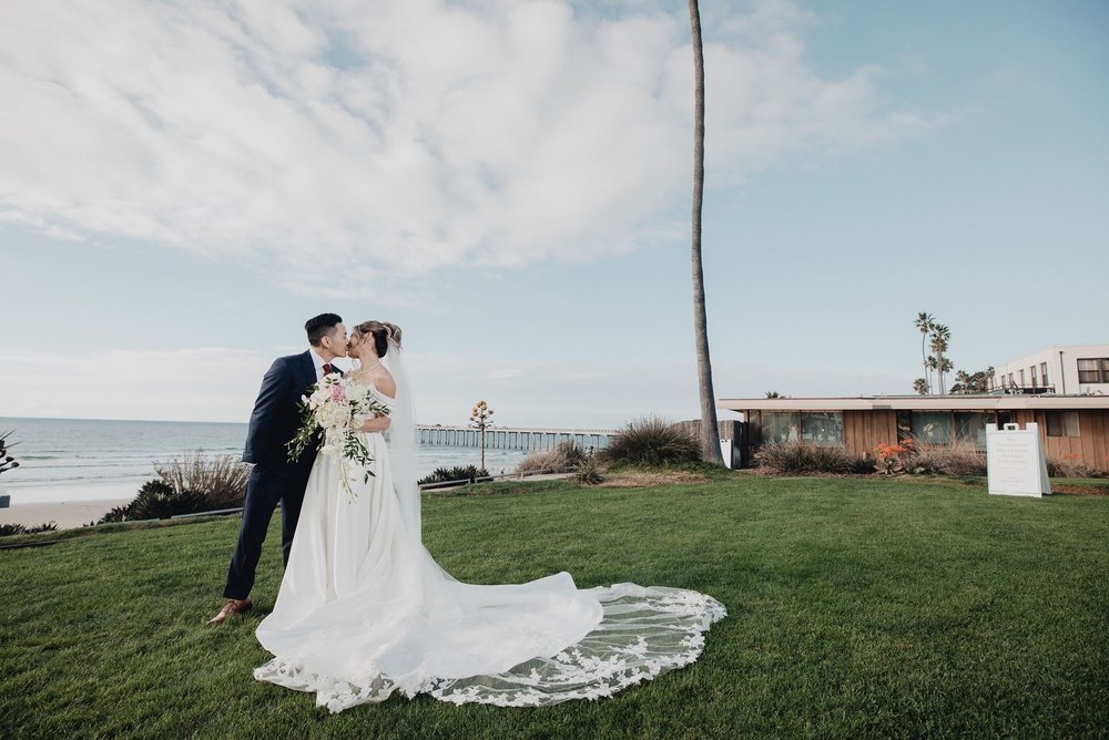 Couple kissing on the lawn at Scripps Seaside Forum above the Pacific