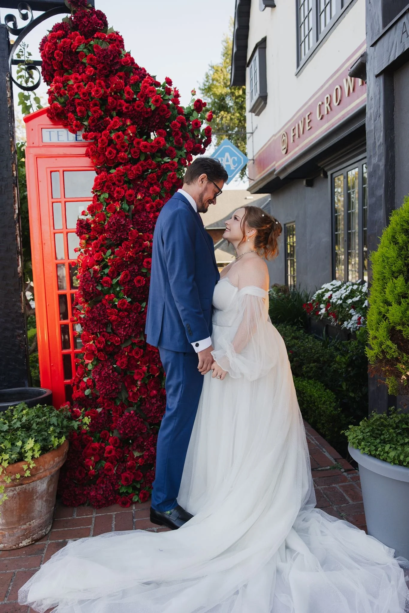 Couple kissing beside the rose-covered red phone box at Five Crowns