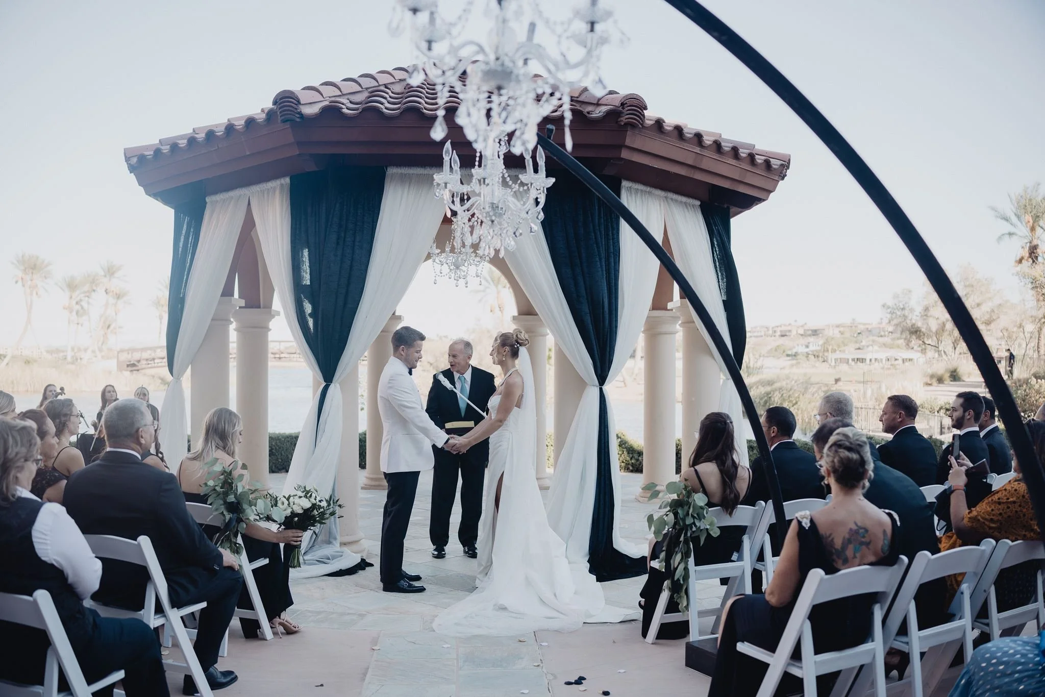 Ceremony under the domed gazebo with navy drapes and a chandelier at Westin Lake Las Vegas