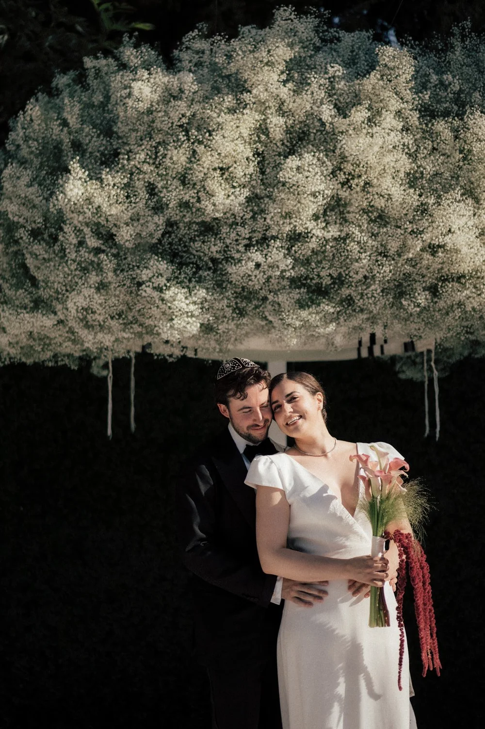 Night portrait of a couple beneath a lit tree after their Jewish wedding