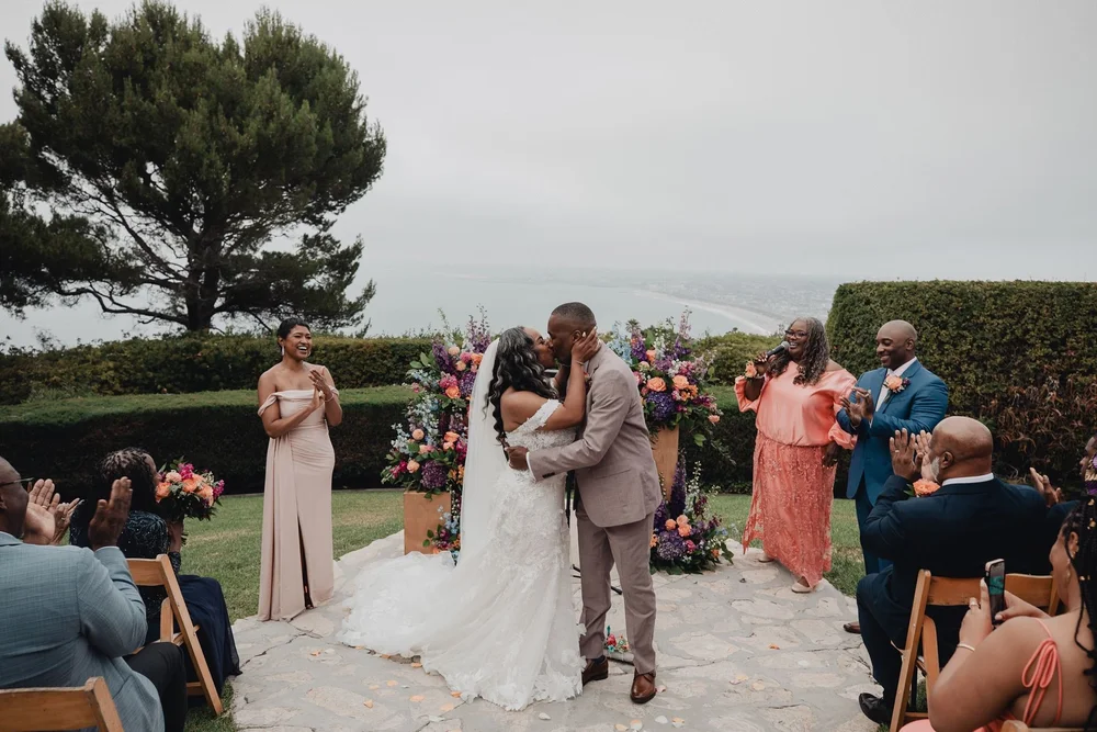 First kiss at a garden ceremony at La Venta Inn as guests cheer