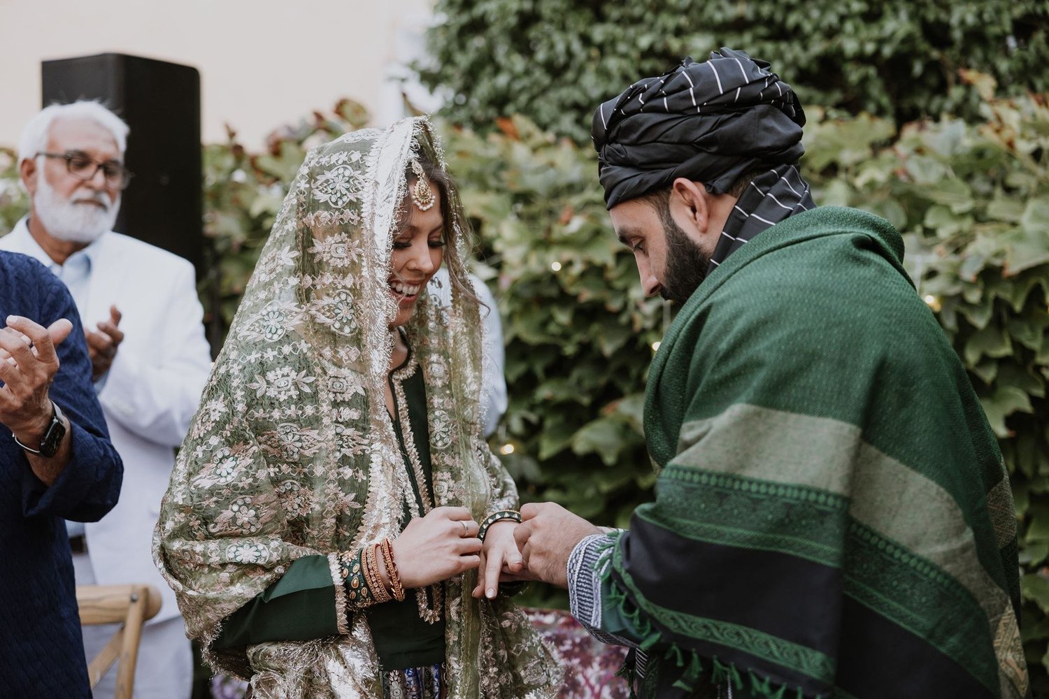 Ring exchange in a garden at a home wedding, family looking on