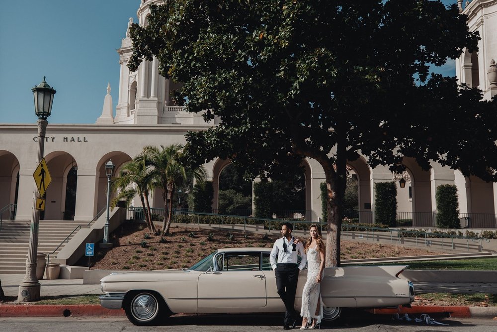 Couple leaning on a vintage white Cadillac outside Pasadena City Hall
