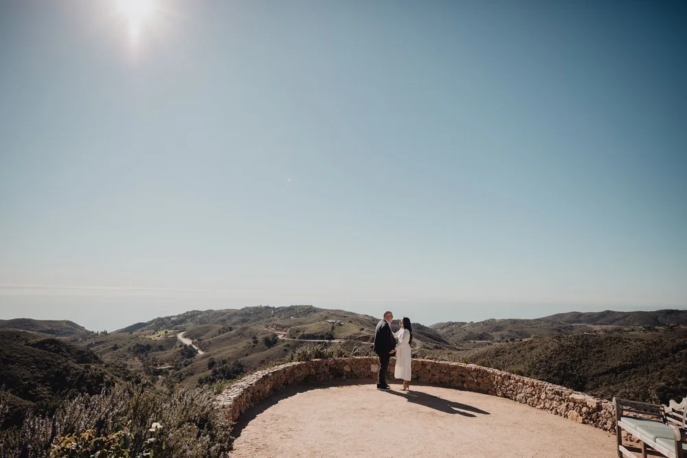 Couple standing on a stone overlook above the Malibu hills at a private ranch estate