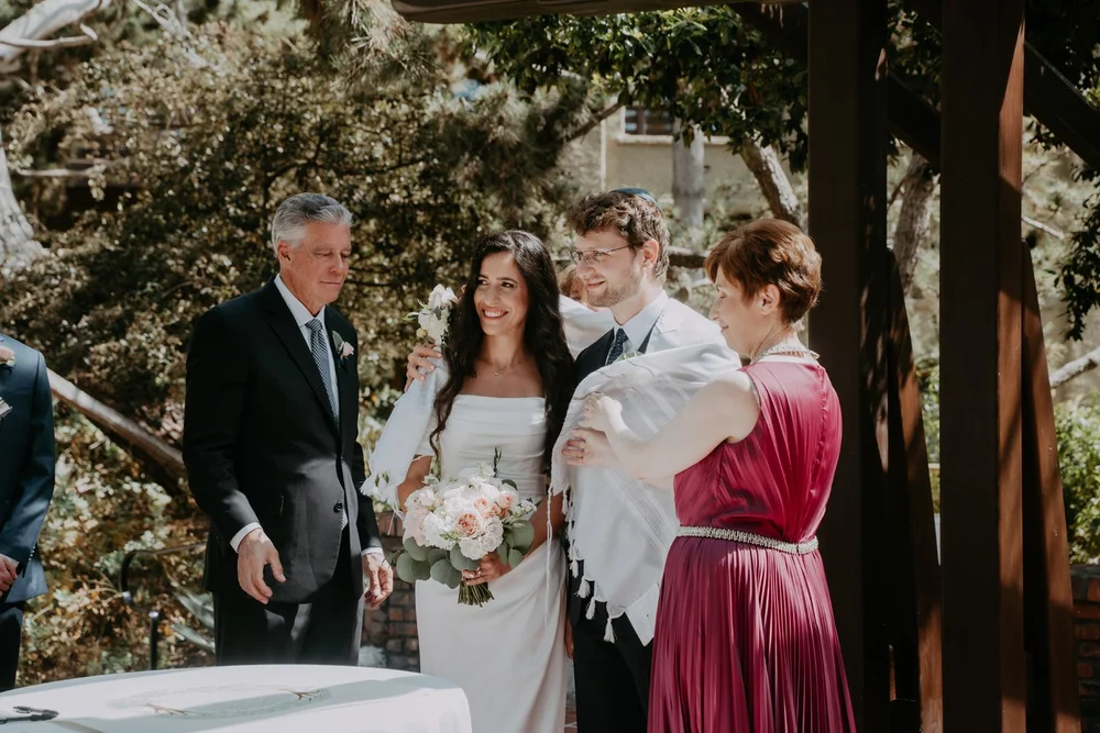 Groom wrapped in a tallit with his parents and family before the ceremony