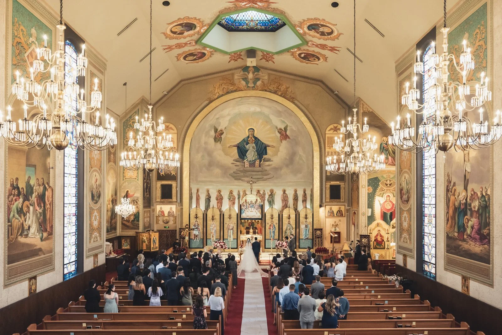 Wedding ceremony under way in a painted church nave with the congregation filling the pews
