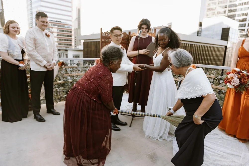 Elders holding the broom on a downtown rooftop at a Nigerian and Filipino wedding