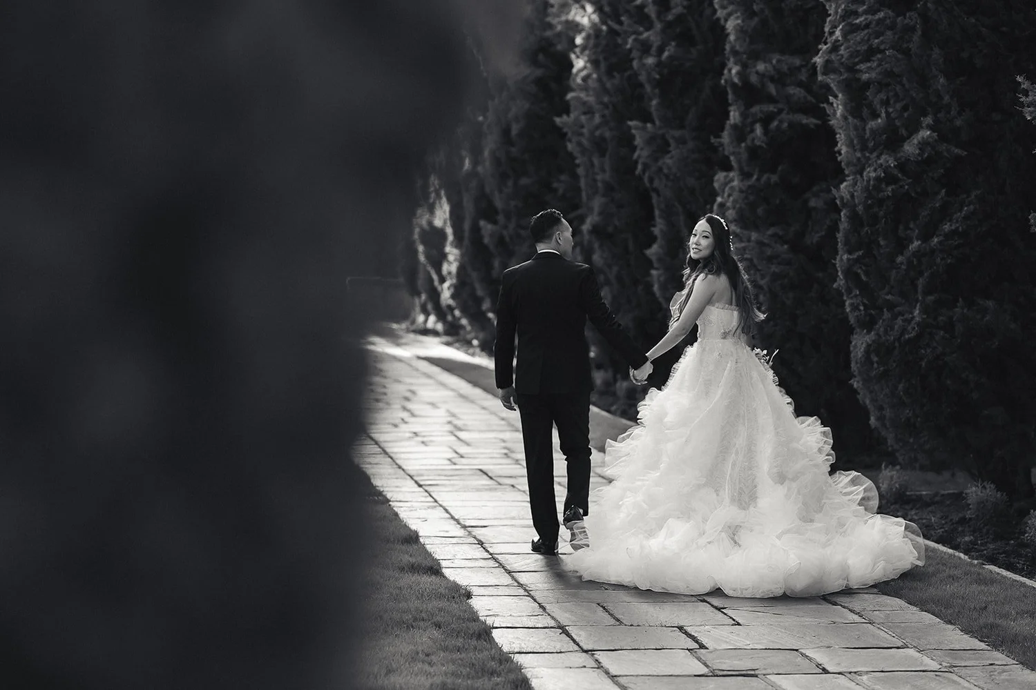 Bride walking the cypress path at Greystone Mansion in black and white