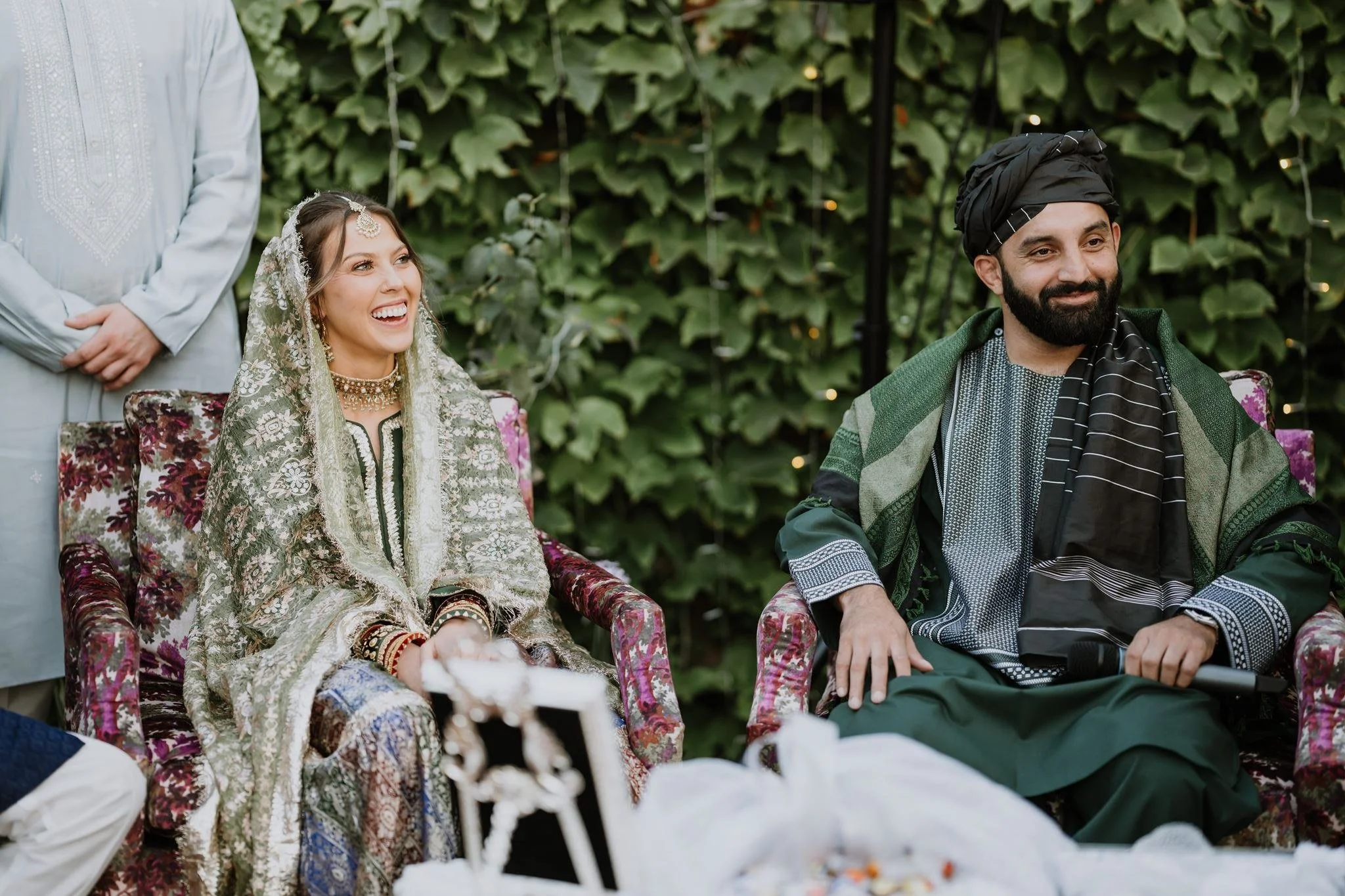 Couple seated beneath an ivy wall during an outdoor nikah at a family home