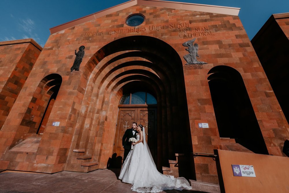 Couple beneath the carved stone arches of St. Leon Armenian Cathedral in Burbank