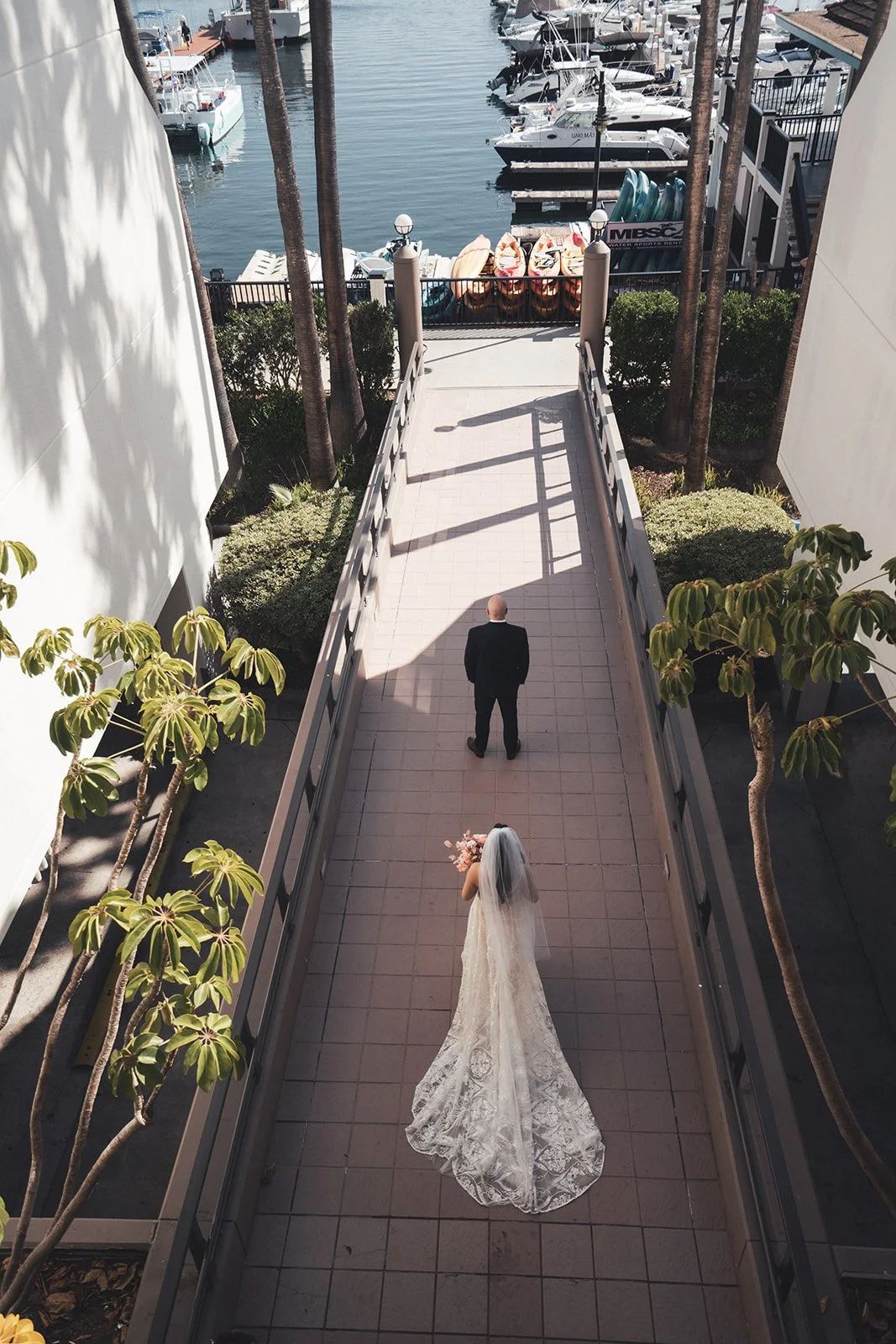 Groom waiting at the end of a long walkway down to the marina as the bride walks toward him at Hyatt Regency Mission Bay