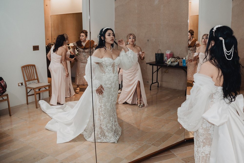 Bride in a white lace fit-and-flare gown with detachable off-the-shoulder sleeves in a mirrored getting-ready room