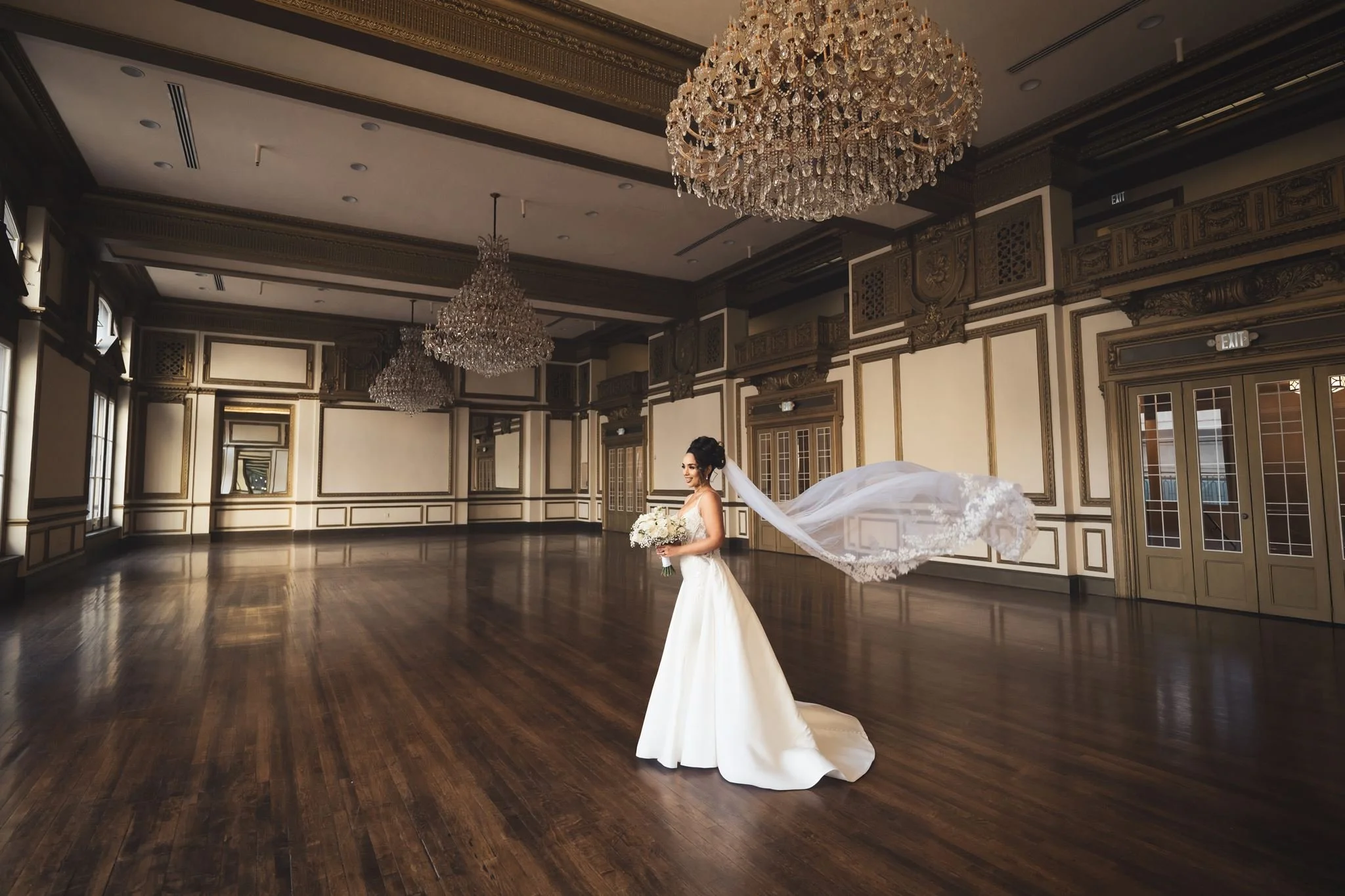 Bride with a flowing veil in an empty chandelier-lit ballroom at Alexandria Ballrooms in Downtown LA