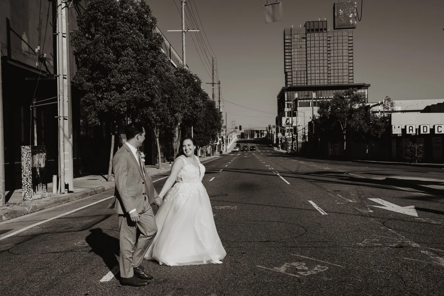 Couple walking down an empty Arts District street with downtown towers behind, black and white