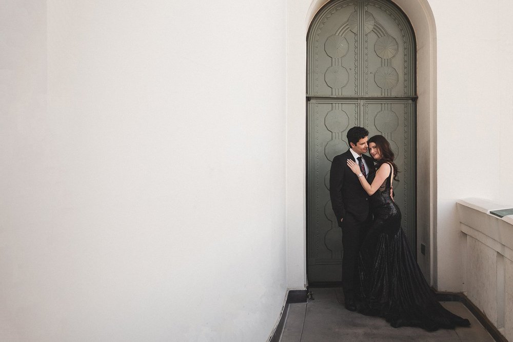 Couple in black formalwear against the arched bronze door of Griffith Observatory