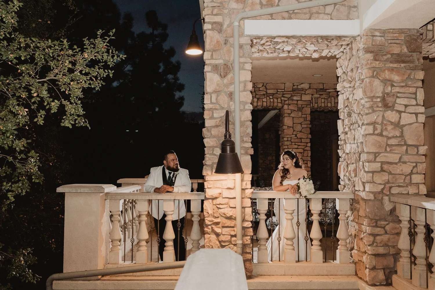 Couple on a stone balcony with lanterns after dark at Vellano Estate