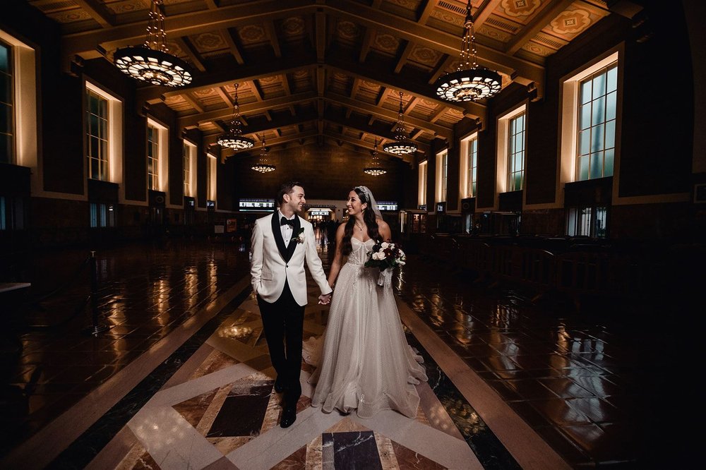 Couple dancing in the grand hall of Los Angeles Union Station beneath its chandeliers
