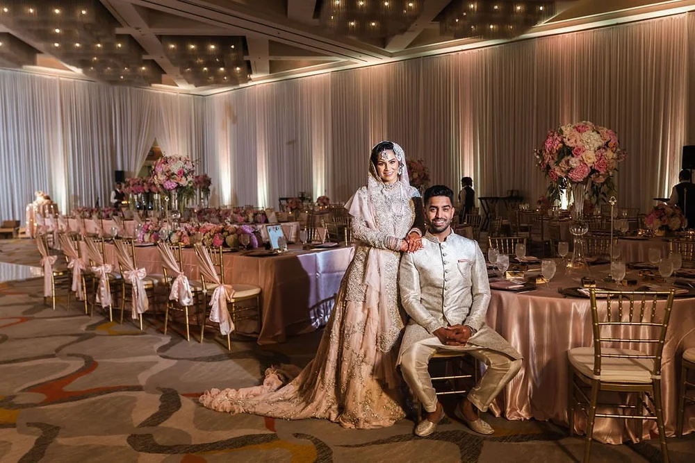 Bride and groom at their sweetheart table in a chandelier-lit ballroom