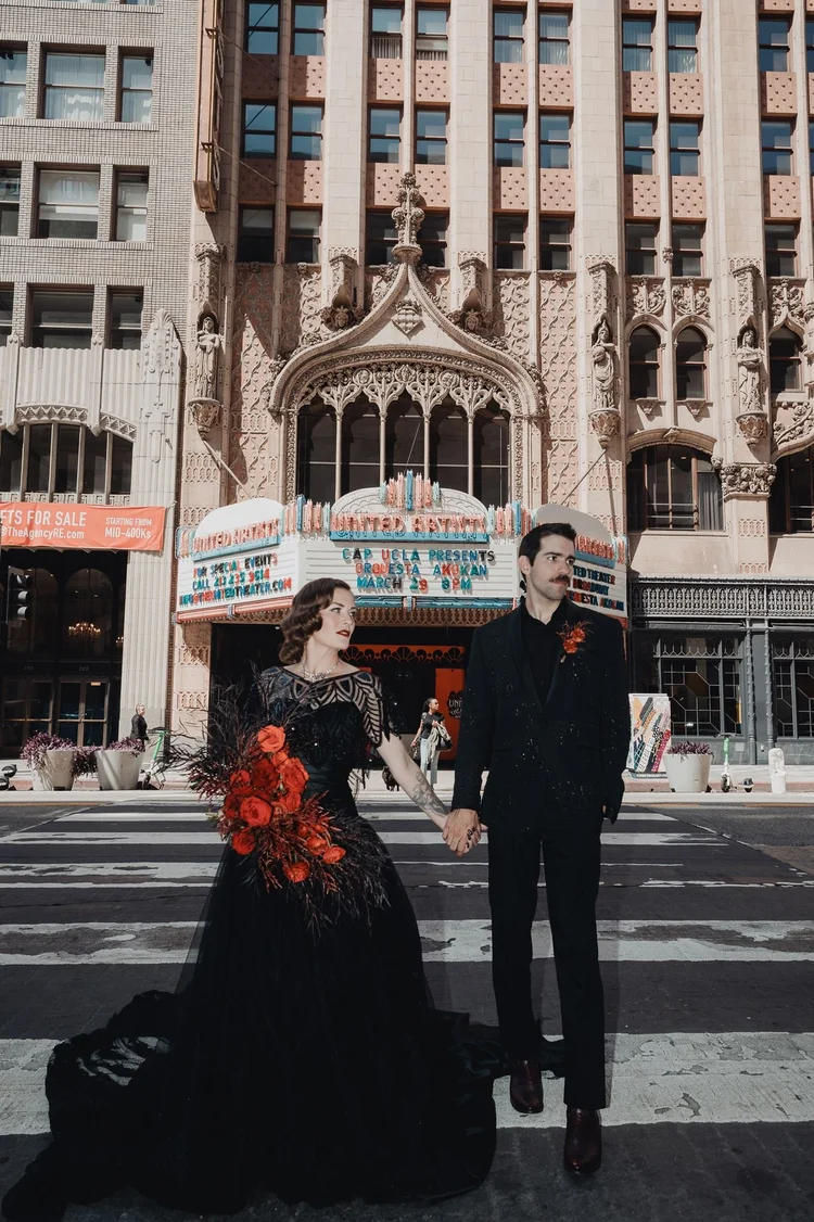 Bride in a black art deco wedding gown beside her husband on a downtown Los Angeles street
