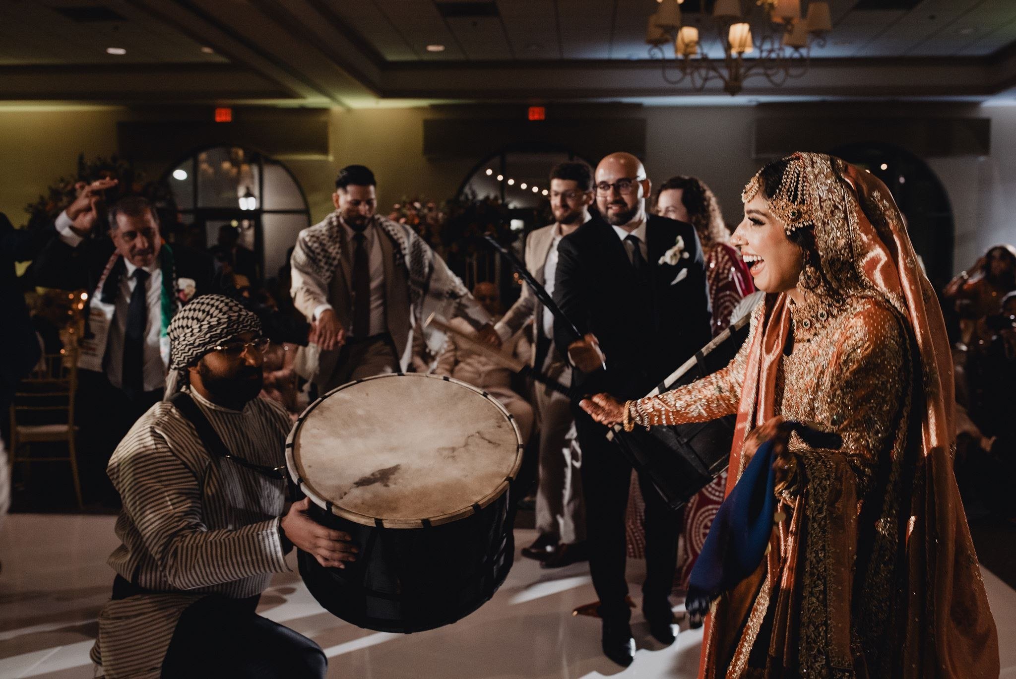 Zaffa drummer in a keffiyeh playing a large tabl as the bride dances into the reception